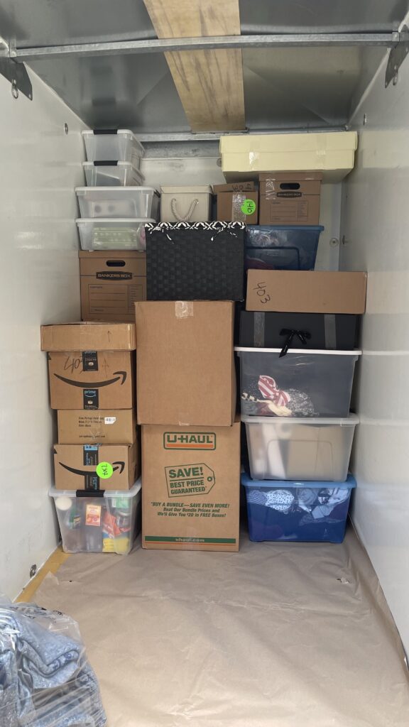 Neatly stacked moving boxes and plastic bins loaded into a moving trailer for a long-distance relocation.